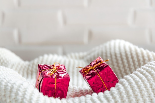 Pequeños regalos en una tela escocesa de punto blanco Pared blanca Cajas rojas Navidad y año nuevo