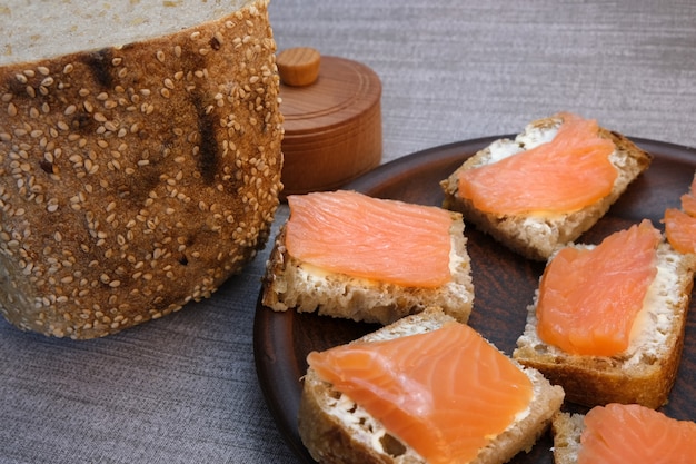 Pequenos sanduíches no pão caseiro com manteiga e peixe vermelho