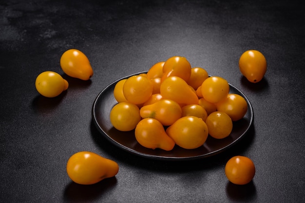 Pequeños tomates amarillos en forma de pera en un plato de cerámica sobre una mesa de hormigón oscuro