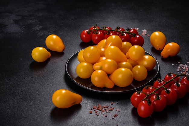 Pequeños tomates amarillos en forma de pera en un plato de cerámica sobre una mesa de hormigón oscuro