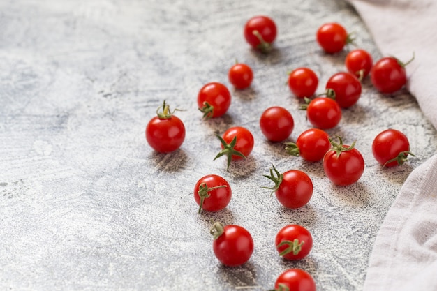 Pequeños tomates cherry (ciliegini, pachino, cóctel). Grupo de tomates cherry en un hormigón gris maduros y jugosos tomates cherry