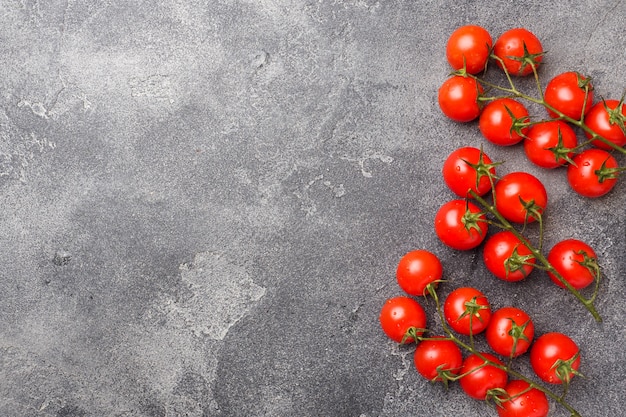 Pequeños tomates cherry rojos en la mesa oscura, vista desde arriba. Copia espacio