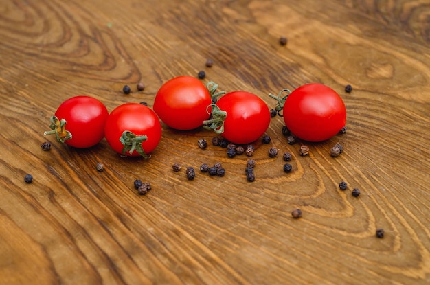 Pequeños tomates cherry rojos sobre fondo de tablero de madera