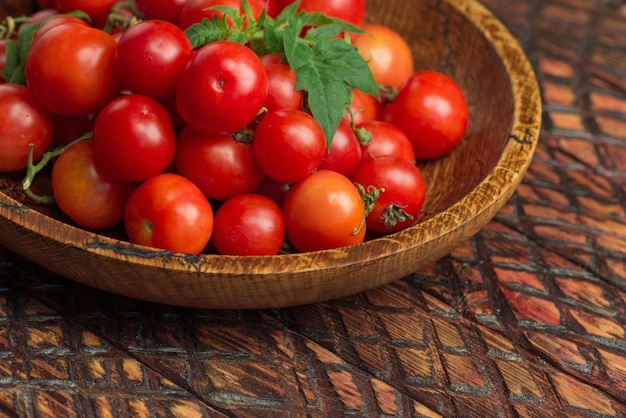 Pequeños tomates frescos en un tazón Tomates cherry en el tazón sobre fondo de madera oscura