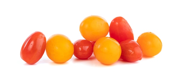 Pequeños tomates rojos y amarillos para picar sobre un fondo blanco.