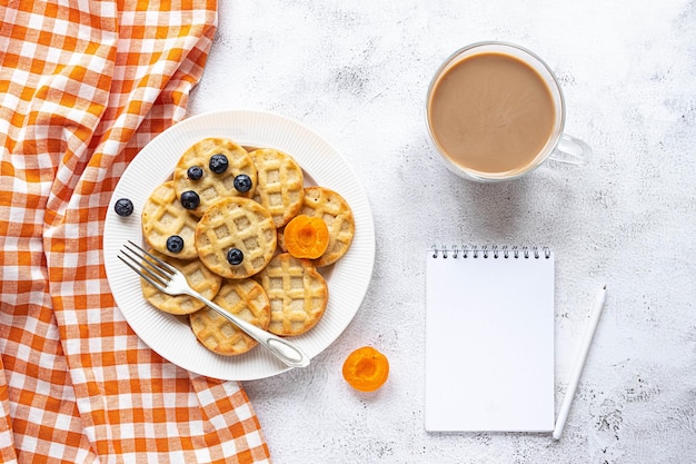 Pequenos waffles redondos e um café em fundo cinza, notebook, flat lay, copie o espaço