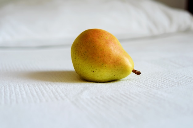 Pêra amarela em um lençol branco na cama.