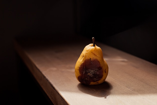 Foto pera amarilla podrida en una mesa de madera