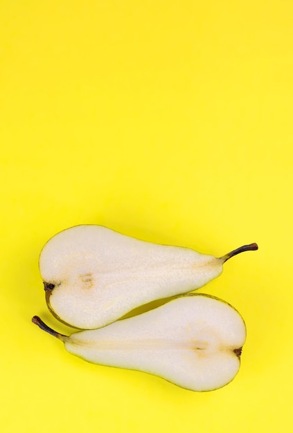 Una pera cortada por la mitad sobre un fondo amarillo.