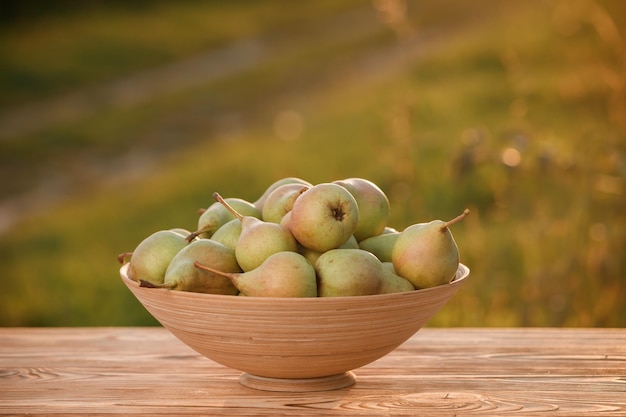 Pera madura fresca na cesta na mesa de madeira com fundo natural do pomar no pôr do sol Composição de frutas vegetarianas Conceito de colheita