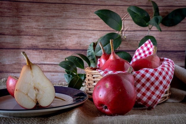 Una pera roja cortada por la mitad y otras jugosas peras rojas en una canasta Productos orgánicos y naturales Comida saludable