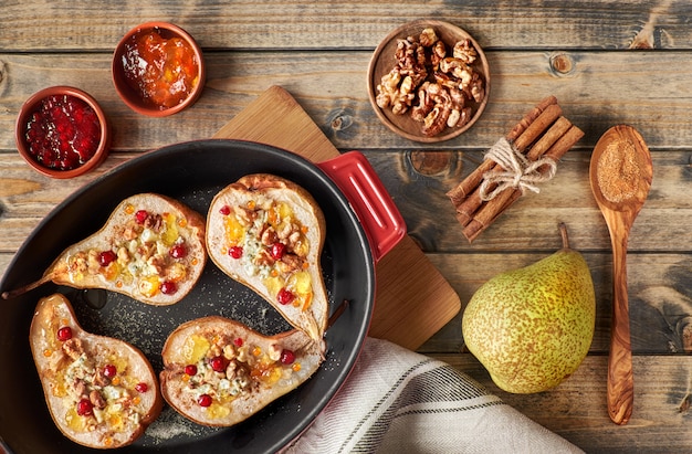 Peras al horno con queso azul, nueces y mermelada en madera