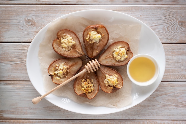 Peras al horno con queso, canela, miel, en un plato blanco.