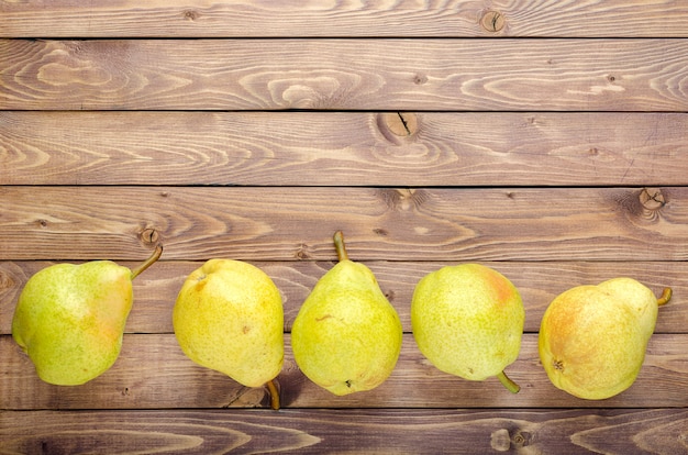 Peras amarillas maduras en fondo rústico de madera. Frutas de verano, cosecha.