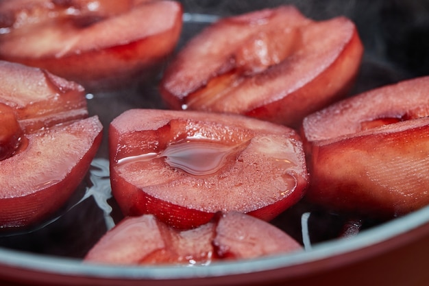 Las peras cortadas se hierven en almíbar rojo con vino en una estufa de gas