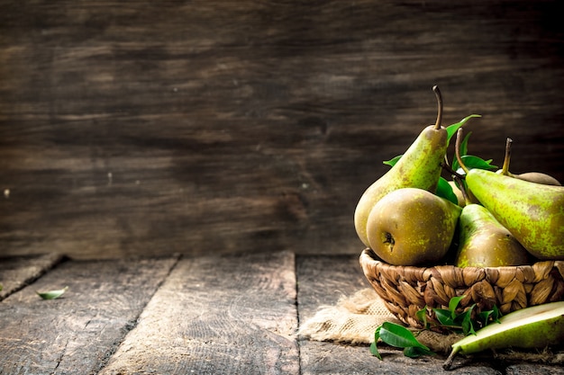 Peras frescas en una canasta sobre mesa de madera.