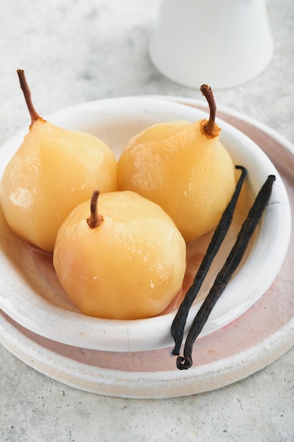 Peras Peras escalfadas en almíbar Servidor de postre tradicional en rodajas en un plato blanco con hojas y en casa sobre un fondo claro Delicioso postre para vacaciones