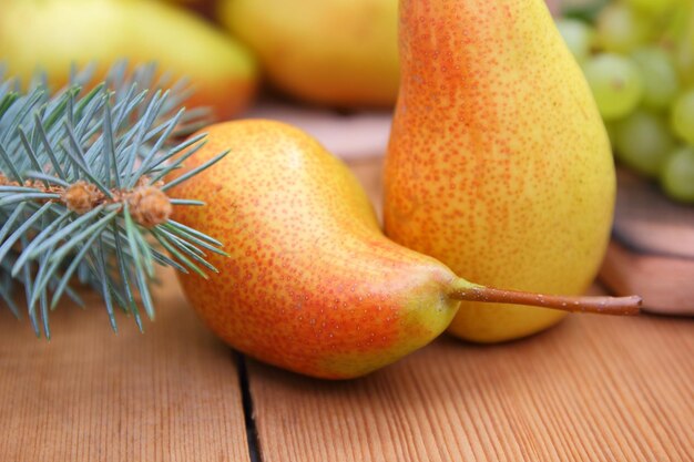 Peras rowan e uvas com folhas e ramos de abeto em um fundo desfocado Cesta com frutas e bagas frescas e suculentas em uma mesa de madeira closeup