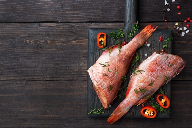 Perca de pescado crudo con eneldo y chiles en una madera.