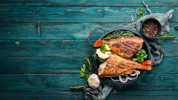 Perca de pescado rojo al horno con verduras en un plato de piedra negra Vista superior Espacio libre para el texto