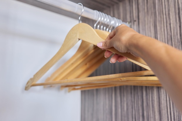 Perchas de madera en un armario abierto vacío mano tomando una percha