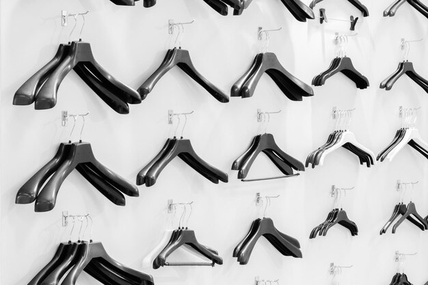 Las perchas de plástico vacías negras se sientan en una pared blanca en un concepto de venta de tienda