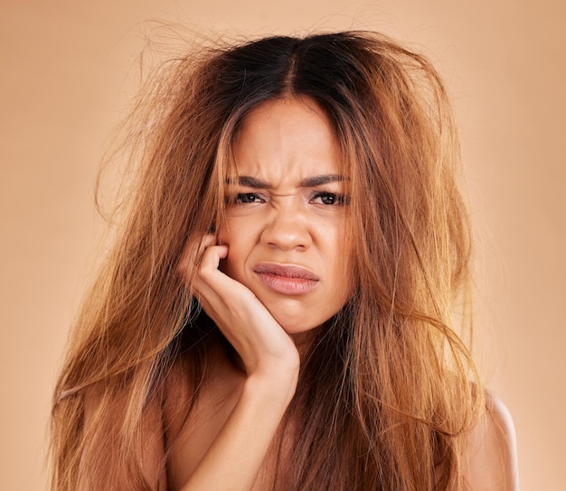 Foto perda de cabelo de retrato facial e mulher triste em estúdio isolado em um fundo marrom dano de queratina de salão e modelo feminino zangado com problema de cabelo penteado bagunçado ou pontas duplas após falha no tratamento