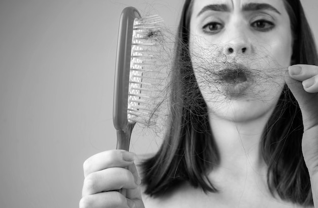 Perda de cabelo Mulher está chateada com a perda de cabelo Retrato de menina triste com cabelo problemático isolado Menina preocupada segurando longos cabelos danificados e não saudáveis na mão