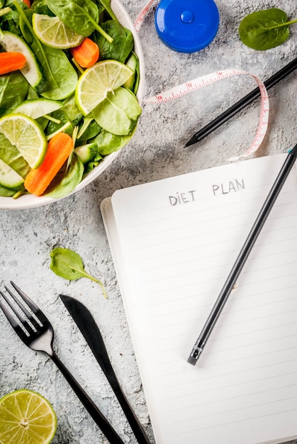 Foto perda de peso de plano de dieta perder conceito, salada de legumes frescos com garfo, faca, bloco de notas, vista superior de espaço de cópia de tabela de pedra cinza