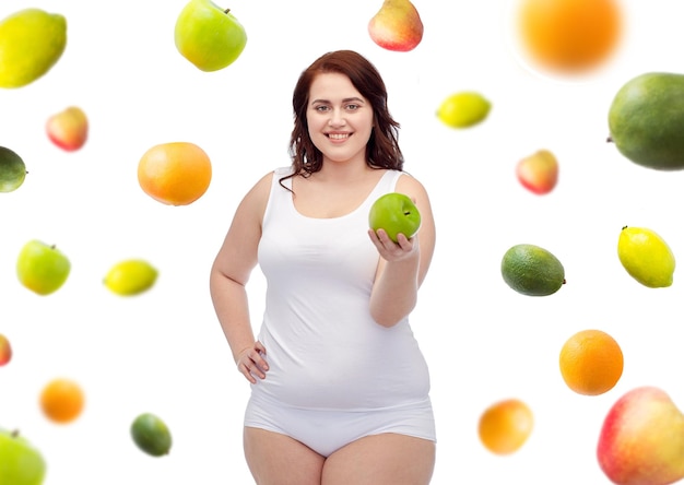 perda de peso, dieta, emagrecimento, alimentação saudável e conceito de pessoas - feliz jovem plus size mulher em cueca com maçã verde sobre fundo de frutas