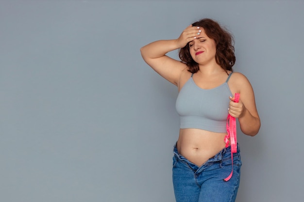 Foto perda de peso e problema de excesso de peso uma mulher gorda em uma regata e jeans está desapontada e chateada com