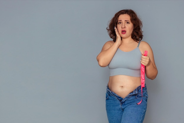 perda de peso e problema de excesso de peso uma mulher gorda em uma regata e jeans está desapontada e chateada com