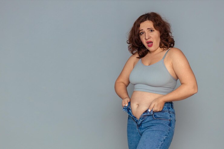 Foto perda de peso e problema de excesso de peso uma mulher gorda em uma regata e jeans está tentando abotoar ou pu