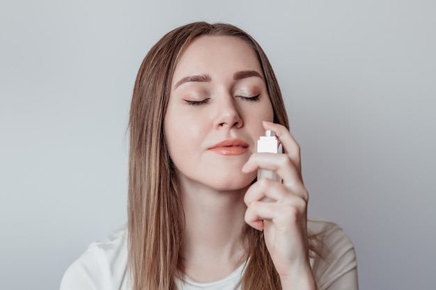 Perda do conceito de cheiro. Jovem caucasiana cheirando perfume isolada