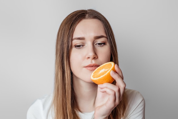 Perda do conceito de cheiro. jovem caucasiana segurando uma laranja perto do nariz isolada