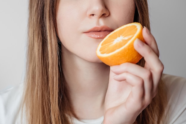 Perda do conceito de cheiro. Jovem caucasiana segurando uma laranja perto do nariz isolada