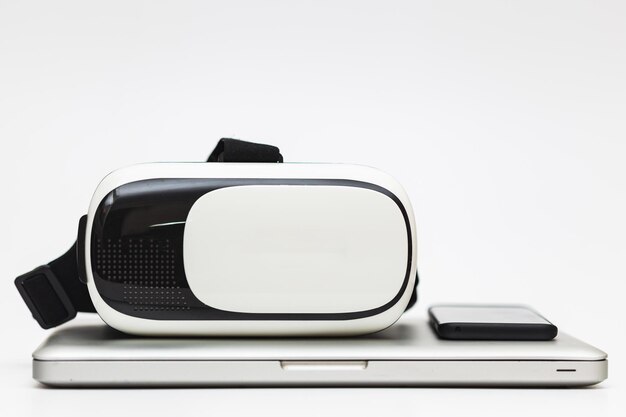 Perder la vista de un VR - gafas de realidad virtual un teléfono inteligente y una computadora portátil sobre un fondo blanco