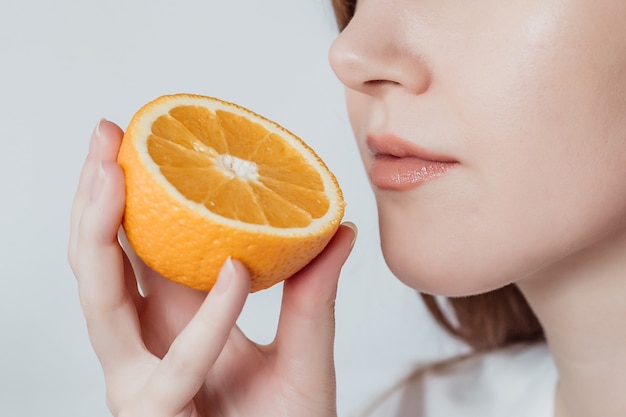 Pérdida del concepto de olfato. Close Up retrato de mujer joven caucásica sosteniendo una naranja cerca de su nariz aislada