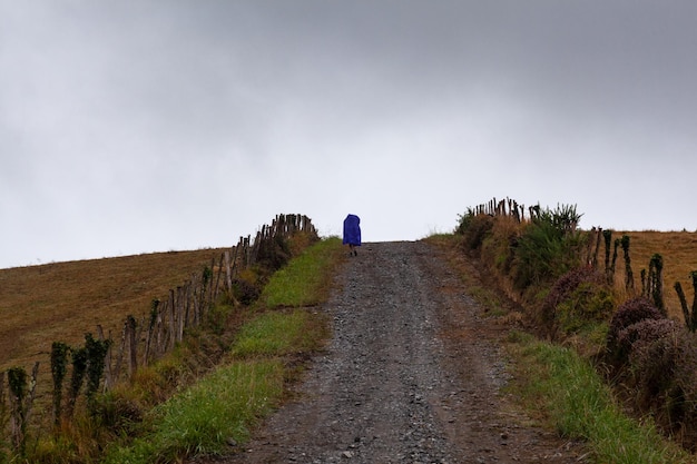 Peregrino andando na estrada rural no dia chuvoso durante o Chemin du Puy França