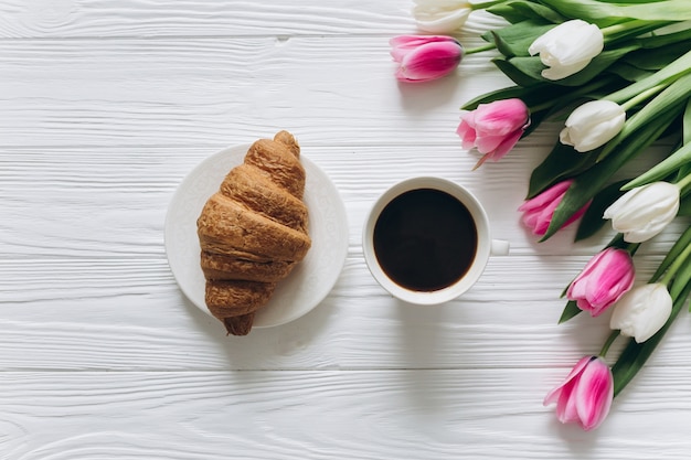 Perfecto desayuno para mujeres. Ramo de tulipanes, café y croissant.