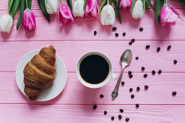 Perfecto desayuno para mujeres. Ramo de tulipanes, café y croissant.