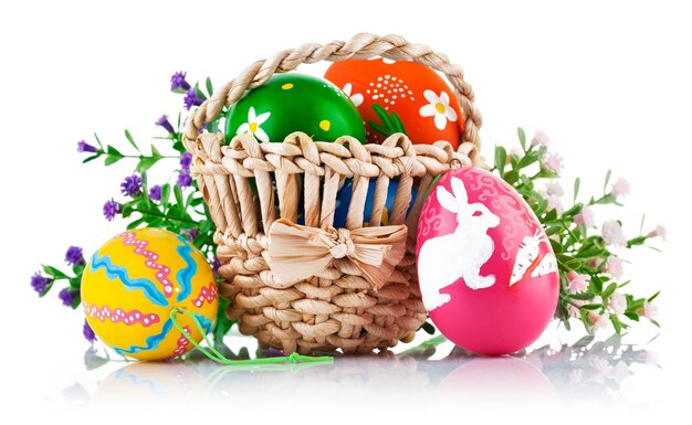 Perfectos huevos de Pascua coloridos hechos a mano en la canasta aislados en un blanco