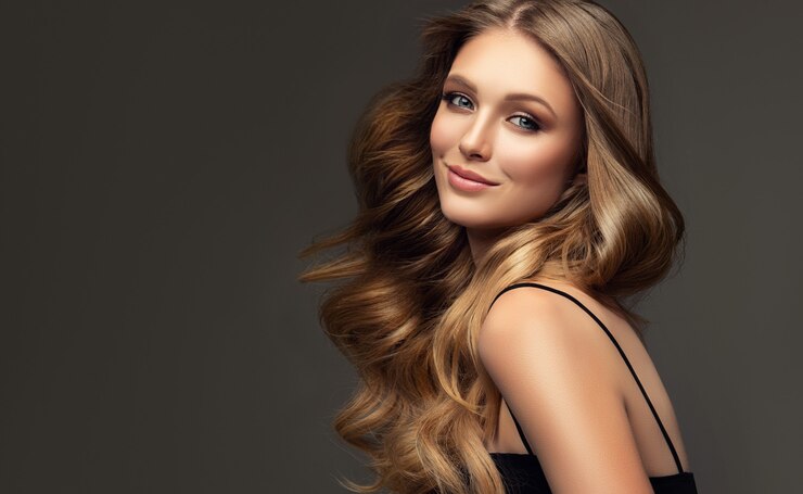 Perfeito bem arrumado cabelo loiro longo e profundo é em torno de um rosto sorridente bonito de jovem mulher