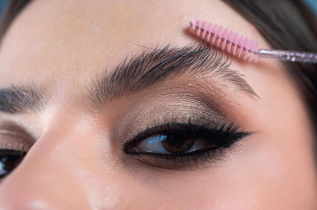 Foto perfekte augenbrauen nahaufnahme einer frau, die augenbrauen-make-up macht makro, die kosmetika mit dem pinsel auf ihre augenbrauen aufträgt perfekte form der augenbrauen braune augenschatten und lange augenbrauen korrektur der augenbrenne