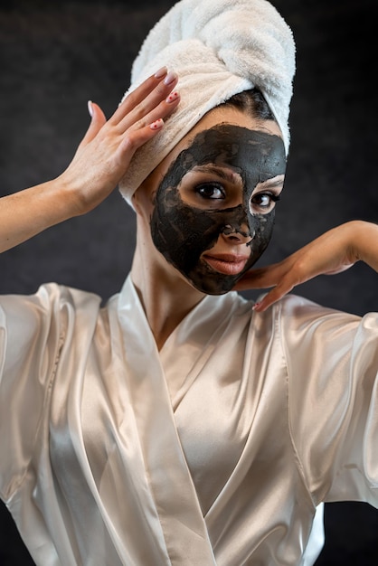 Perfekte Behandlung zur Befeuchtung der Haut für jede Frau mit einer schwarzen Tonmaske. Spa-Anti-Aging-Behandlung