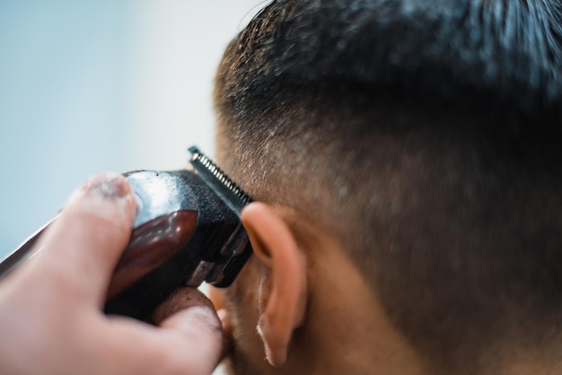 Perfekte Form bekommen. Nahaufnahme des jungen bärtigen Mannes, der vom Friseur im Friseursalon Barthaarschnitt erhält. Weicher Fokus.