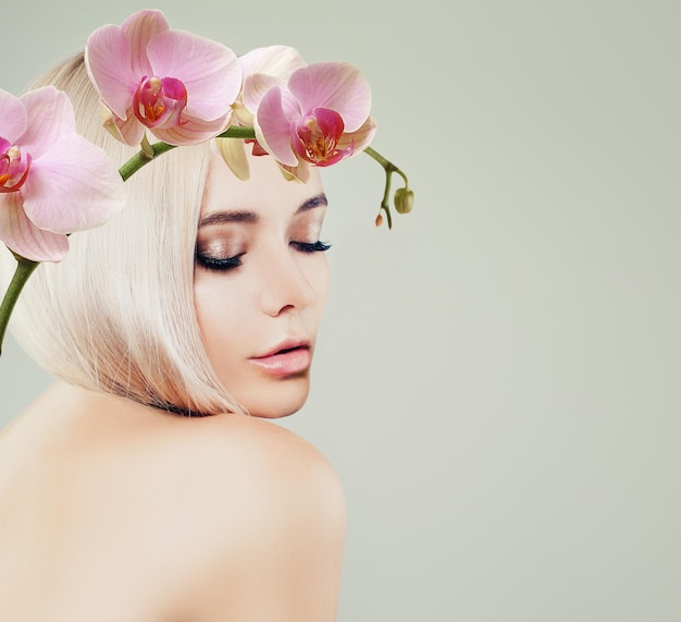 Perfekte junge Frau mit gesundem blondem Haar und rosafarbenen Orchideenblüten auf Bannerhintergrund