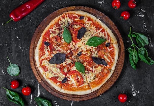 Perfekte Pizza Margarita mit Tomatenscheiben Basilikum auf einer dunklen Oberfläche
