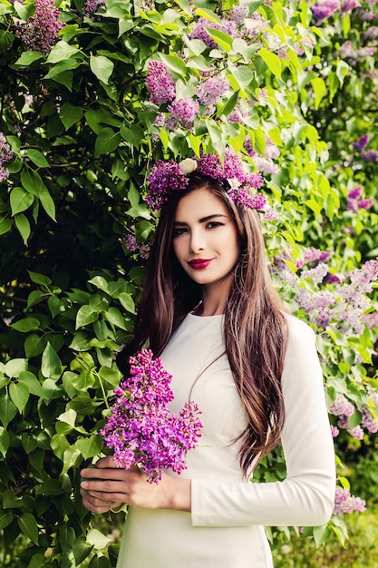 Perfekte weibliche vorbildliche Frau mit lila Frühlingsblumen im Freien Langes, gesundes Haar-Make-up