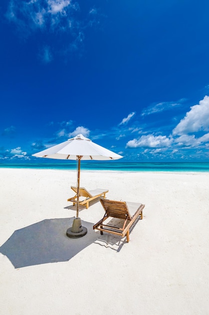 Perfekter tropischer Strand Sommerlandschaft mit Stühlen und Sonnenschirm auf weißem Sand in der Nähe des blauen Meereshimmels